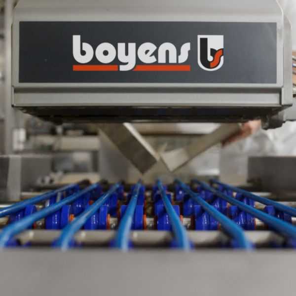 Boyens-Maschine mit Firmenlogo über einem Förderband mit blauen Führungsstangen