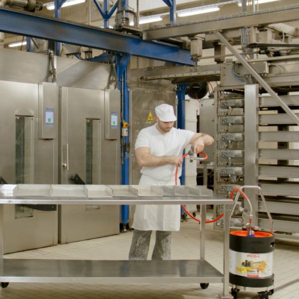 Bäcker sprüht Boyens PCO-I Trennmittel aus dem Fass in Backformen